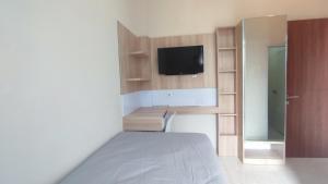 1 dormitorio con 1 cama y TV en la pared en Shofa boarding house syariah, en Jenggrik