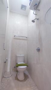 y baño blanco con aseo y ducha. en Shofa boarding house syariah, en Jenggrik
