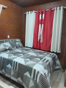 um quarto com uma cama e uma cortina vermelha e branca em Cabanas dos Pinheiros em São Francisco de Paula