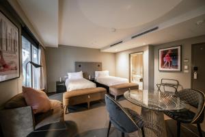um quarto de hotel com duas camas e uma mesa e cadeiras em The Kinson em Melbourne