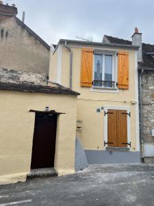 uma casa amarela com uma porta preta e janelas em Escapade Moretaine - 22 Langin em Moret-sur-Loing