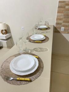 a table with plates and wine glasses on a counter at FLATS VALLE DEL SOL in Japaratinga
