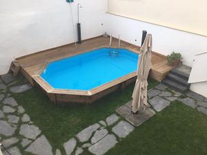 een klein zwembad met een houten terras en een parasol bij Covil's Haus in Peniche