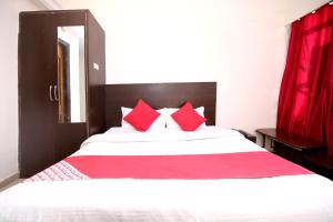 um quarto com uma grande cama branca com almofadas vermelhas em OYO Hotel Dwarika Inn em Jabalpur