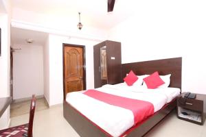 una camera da letto con un grande letto con cuscini rossi di OYO Hotel Dwarika Inn a Jabalpur