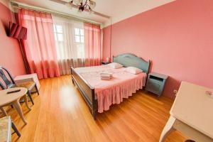 a bedroom with a bed with pink walls and wooden floors at Viktorija in Riga +183 photos