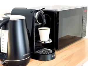 Modern Studio with Mountain View and Near Airport & CBD في Warrane: وجود آلة صنع القهوة بجانب ميكروويف