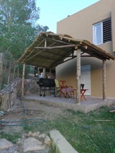 pérgola de madera en un patio frente a una casa en Casa en Cuesta Blanca dos dormitorios en Villa Icho Cruz