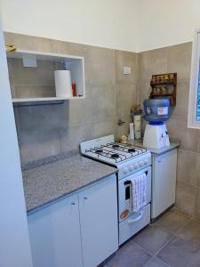 cocina con fogones y armarios blancos en Casa en Cuesta Blanca dos dormitorios en Villa Icho Cruz