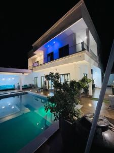 une grande maison avec une piscine la nuit dans l'établissement VILLA NAYFAL, à Saly Portudal