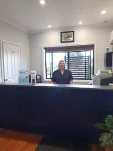 Eine Frau, die hinter einem Tresen in einem Büro steht. in der Unterkunft Golden Reef Motor Inn in Bendigo