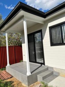 a front porch of a house with a red fence at Fragrant Home-68A Brand New 2 rooms House with beautiful private garden and entrance,5G wifi in Doonside