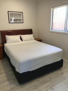 a bedroom with a large bed with white sheets at Fragrant Home-68A Brand New 2 rooms House with beautiful private garden and entrance,5G wifi in Doonside