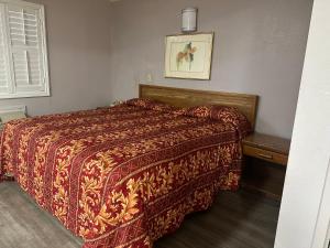 Schlafzimmer mit einem Bett mit einer roten Bettdecke in der Unterkunft Plaza Inn Motel - Los Angeles area in Rosemead
