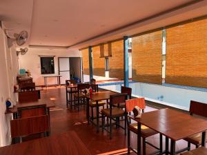 a restaurant with wooden tables and chairs and windows at Jasmine Vangvieng Hotel in Vang Vieng
