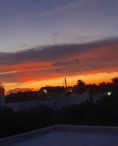 um pôr-do-sol sobre uma casa com uma piscina em primeiro plano em Casa Calandria em Chicxulub