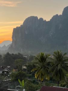 a view of a mountain with palm trees in the foreground at Jasmine Vangvieng Hotel in Vang Vieng