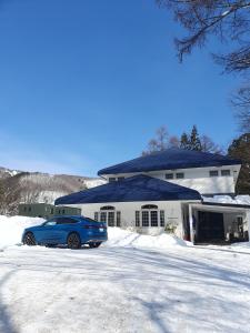 un coche azul estacionado frente a una casa en Luna Lodge en Hakuba