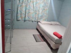 ein kleines Bett in einem Zimmer mit Dusche in der Unterkunft Green Lodge Holiday Homes in Nuku‘alofa