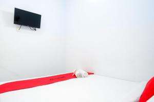 a red baseball bat sitting on a bed with a tv at RedDoorz near Puri Anjasmoro Area Semarang in Semarang