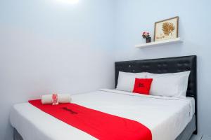 a bedroom with a bed with a red blanket on it at RedDoorz near Puri Anjasmoro Area Semarang in Semarang