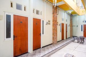 a corridor of a building with wooden doors and chairs at RedDoorz near Puri Anjasmoro Area Semarang in Semarang