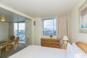 1 dormitorio con cama, escritorio y ventana en Ilikai Marina 380 Yacht Harbor View 1BR, en Honolulu