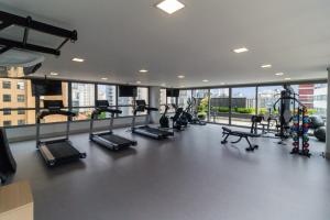 una palestra con un mucchio di tapis roulant e macchine di Cozzy Suites Paraíso Hotel a San Paolo