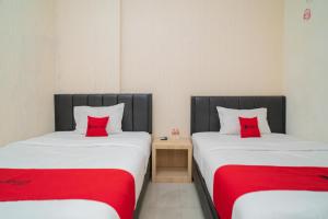 2 camas con almohadas rojas en una habitación en RedDoorz near Flyover Arjosari Malang, en Malang