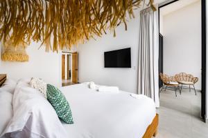 a bedroom with a white bed and a tv on the wall at The mVilla with Exclusive Beach Club Access in Tamarindo