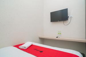 Habitación con cama y TV en la pared. en RedDoorz near Matahari Singosaren Solo, en Solo
