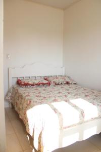 een bed in een witte kamer met een sprei bij Apartamento em Torres in Torres