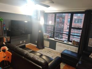 sala de estar con sofá de cuero y TV en Lovely one bedroom apartment in Westchester, NY! en Ossining