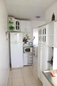 een keuken met witte kasten en een witte koelkast bij Apartamento em Torres in Torres