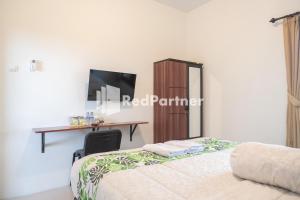 a bedroom with two beds and a desk and a table at Twin House near UII Yogyakarta Mitra RedDoorz in Yogyakarta