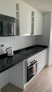 a kitchen with white cabinets and a black counter top at Departamento estudio IslaTeja in Valdivia