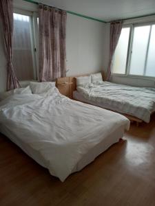 two beds sitting in a room with windows at Jemulpo house - Foreigner Only in Incheon