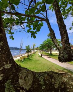 un parque con árboles y una acera junto a la playa en Solarium Flats Itagua - Ubatuba SP, en Ubatuba