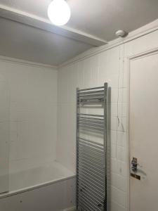 a bathroom with a shower and a white tiled wall at Balham, South London Spacious Guest House 1 in London