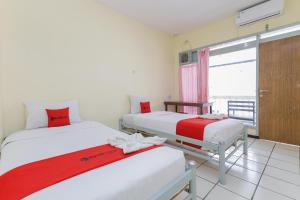 two beds in a room with a window at RedDoorz at CBR Residence Blimbing in Malang