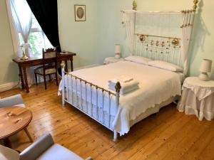 Schlafzimmer mit einem weißen Bett und Holzboden in der Unterkunft Lorelei Bed & Breakfast in Portland