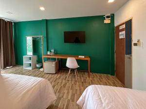 Plernpetch Hotel في سوراثاني: غرفة بها مكتب وجدار أخضر