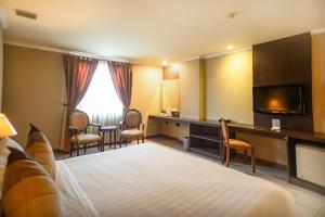 ein Hotelzimmer mit einem Bett und einem Flachbild-TV in der Unterkunft Olympic Hotel in Jakarta