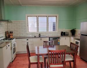 a kitchen with a table and chairs and a refrigerator at Coco's Cottage in Tamworth