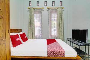 GlagahにあるOYO 92071 Yusman Homestay Syariahのベッドルーム(赤い枕のベッド1台、テレビ付)