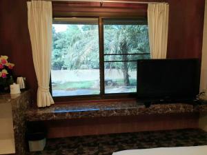 a bedroom with a window with a flat screen tv at Pechpailin Resort in Kanchanaburi City