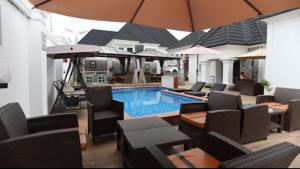 una piscina con sillas, mesas y sombrilla en Kawruky Hotel Guobadia, en Benin City