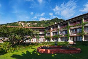 ein Gebäude mit einem Brunnen in der Mitte eines Gartens in der Unterkunft Hotel Atitlan in Panajachel