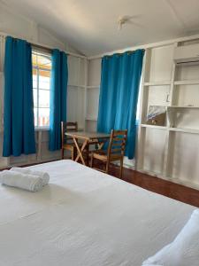a bedroom with a bed and a table and blue curtains at Christina's Guest House OFFICIAL in Little Corn Island