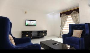a living room with two blue chairs and a tv at Kawruky Hotel Guobadia in Benin City